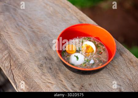 Selektiver Fokus Hackbrei im thailändischen Stil mit gekochtem Ei. Das Frühstück in einer orangen Tasse hilft, Energie zu steigern Stockfoto