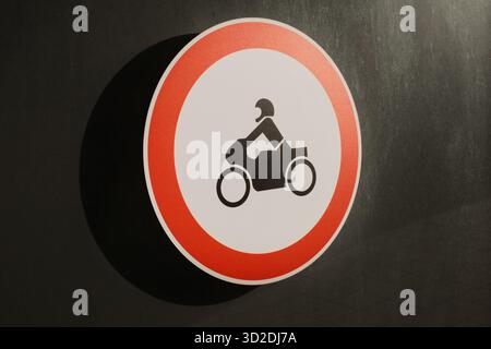 Rundes Verkehrsschild, das Motorräder auf dunklem Stadtmauergrund verbietet. Stockfoto