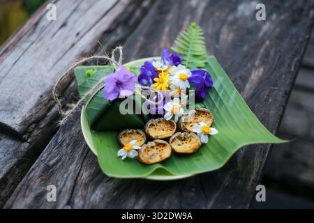 Selektiver Fokus Ricefield-Krabben in ihren Muscheln. Sehen Sie Na beim Essen zu und dekorieren Sie den Teller mit natürlichen Blumen. Essen Sie mit klebrigem Reis, der in Bananenlaub gewickelt ist Stockfoto