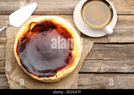 Leckerer baskischer Käsekuchen, Tasse Kaffee und Spatel auf Holztisch, flacher Lay Stockfoto