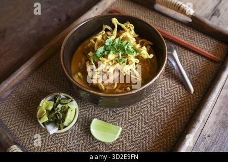 Köstliches Khao Soi, herzhaftes thailändisches Essen mit Noodle Curry Suppe. Diese traditionelle asiatische Küche in einer Schüssel mit Limette und Gurke bietet einen Appet Stockfoto