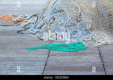 Ein großer Stapel von Fischernetzen mit Schwimmern liegt auf einem Holzsteg gesammelt. Stockfoto
