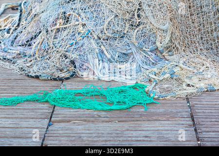 Ein großer Stapel von Fischernetzen mit Schwimmern liegt auf einem Holzsteg gesammelt. Stockfoto