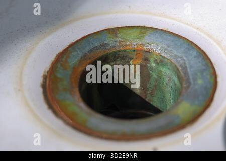Eine schmutzige Makroansicht eines alten Ablauflochs zeigt Rost und grüne Patina durch Korrosion. Vernachlässigte Metallinstallationen vermitteln ein Gefühl von Zerfall und g Stockfoto