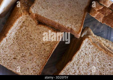 Gesunde Nahaufnahme von frisch geschnittenem braunem Brot. Hintergrund zeigt Stapel Vollkornbrot perfekt für gesunde Ernährung, Sandwich, Frühstück und Nuss Stockfoto