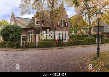 Eckblick auf ein bezauberndes traditionelles holländisches Haus in Haarzuilens mit markanten rot-weiß gestreiften Fensterläden und einem klassischen Laternenpfosten. Stockfoto