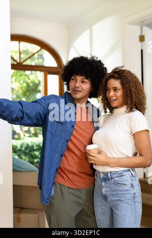 Junge, vielfältige Paare, die Kisten in einem neuen Zuhause auspacken, lächeln und den Moment genießen. Bewegen, Verschieben, Neuanfänge, Glück, Zweisamkeit || Model veröffentlicht Stockfoto