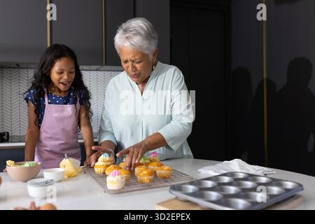 Cupcakes dekorieren, Großmutter und Kind in der modernen Küche, Zeit miteinander verbringen. Backen, Familie, Bonding, kulinarische Spezialitäten, Süßigkeiten, Dessert || Modell veröffentlicht Stockfoto