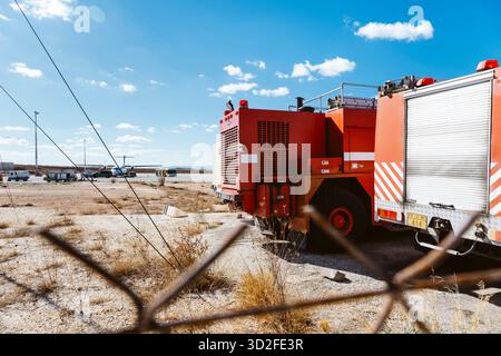 Zwei Feuerwehrfahrzeuge parken hinter dem Stacheldrahtzaun am Flughafen Paros, Griechenland. Stockfoto