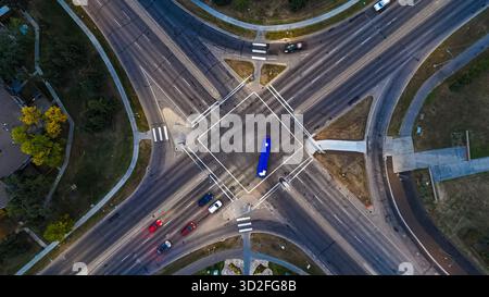 Drohnenblick auf den Verkehrsübergang an einer breiten Kreuzung mit Stadtampeln in der Abenddämmerung Stockfoto