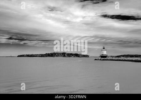Schwarzweißbild des Spring Point Ledge Lighthouse in Portland, Maine, das den Kontrast zwischen hellem Himmel und reflektierendem Hafenwasser unterstreicht Stockfoto