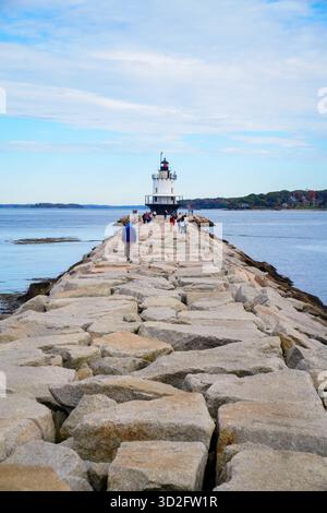Besucher spazieren entlang der langen felsigen Mole, die zum Spring Point Ledge Lighthouse führt, mit Blick auf Casco Bay an einem Herbstnachmittag Stockfoto