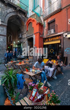 Ein Blick auf eine Aperitif-Bar an der Via dei Tribunali im historischen Zentrum von Neapel mit einigen Touristen. Stockfoto