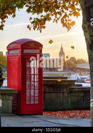 Herbst in London, England, Konzept mit einer roten Telefonzelle vor dem Big Ben Turm während des goldenen Oktoberuntergangs Stockfoto