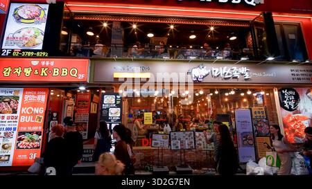 SEOUL, SÜDKOREA - 11. OKTOBER. 2025 - Menschen genießen koreanisches BBQ und jokbal in Restaurants entlang einer belebten Straße in Myeongdong, Seoul Stockfoto