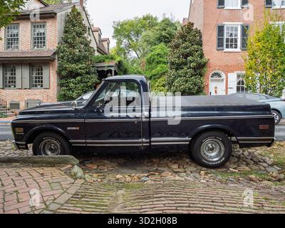 Seitenprofil eines klassischen dunkelblauen Chevrolet Cheyenne Pickup Trucks mit Chromverkleidung, geparkt auf einer kopfsteingepflasterten Straße, die von Ziegelhäusern in New CA begrenzt ist Stockfoto