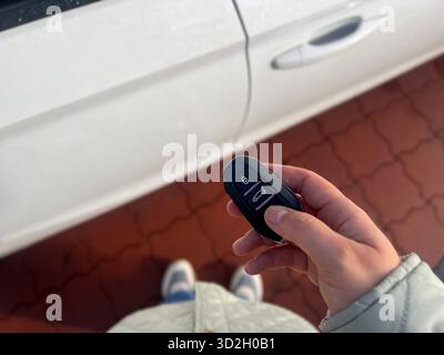 Nahaufnahme einer weiblichen Hand, die einen Autoschlüssel hält und das Auto entriegelt Stockfoto