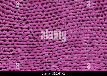 Makro, Nahaufnahme, detailliertes rosafarbenes Stricktextil, Stoffstruktur mit grobem Garnmuster. Gemütlicher handgemachter Stoffhintergrund, Strickhintergrund, pe Stockfoto