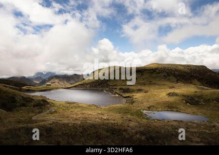 Hochgebirgssee umgeben von páramo Grasland und Bergen unter dramatischen Wolken im Cayambe-Coca Nationalpark, Ecuador. Stockfoto