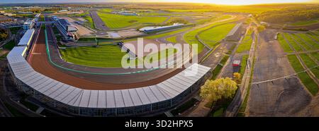 Blick aus der Vogelperspektive auf den Silverstone Circuit im frühen Morgenlicht, mit Tribünen, Grubengebäuden und Streckenlayout. Ideal für Motorsport-Themen Stockfoto