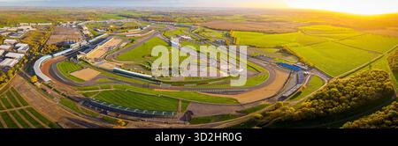Blick aus der Vogelperspektive auf den Silverstone Circuit im frühen Morgenlicht, mit Tribünen, Grubengebäuden und Streckenlayout. Ideal für Motorsport-Themen Stockfoto