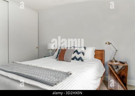Modernes Wüstenschlafzimmer mit Holzrahmen Bett Akzent Kissen werfen Decken Lampen seitlich Blick Stockfoto