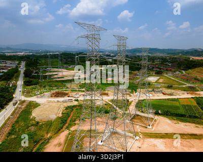 Luft- und Bodenansicht der Hochspannungs-Übertragungstürme im ländlichen Malaysia mit Darstellung der Elektrizitätsinfrastruktur und des Stromverteilungsnetzes. Stockfoto