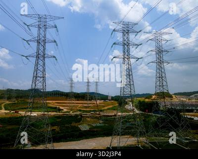 Luft- und Bodenansicht der Hochspannungs-Übertragungstürme im ländlichen Malaysia mit Darstellung der Elektrizitätsinfrastruktur und des Stromverteilungsnetzes. Stockfoto