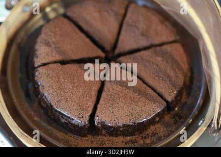 Dekadenter hausgemachter Schokoladenkuchen, reichhaltiges Torte-Dessert, bedeckt mit Kakaopulver. Köstliches Gourmet-Gebäck, in perfekte Scheiben geschnitten, bereit für süße Köstlichkeiten Stockfoto