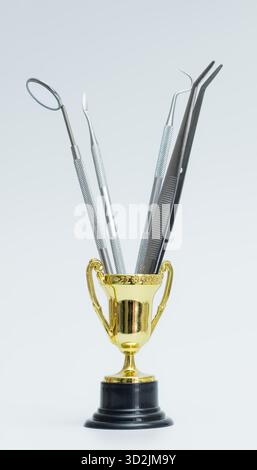 Goldene Trophäe kreativ verwendet, um Edelstahl-Dentalinstrumente zu halten, symbolisiert Exzellenz in der Zahnmedizin und Mundheilkunde Praxis. Stockfoto
