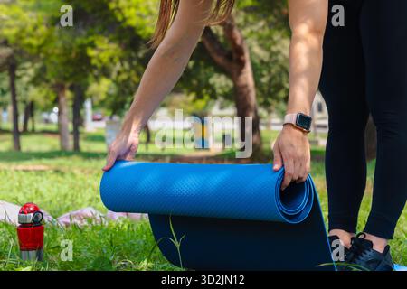 Sportliche Frau, die im Freien Yoga-Matte vorbereitet, sich vor dem Training im Park dehnt. Stockfoto