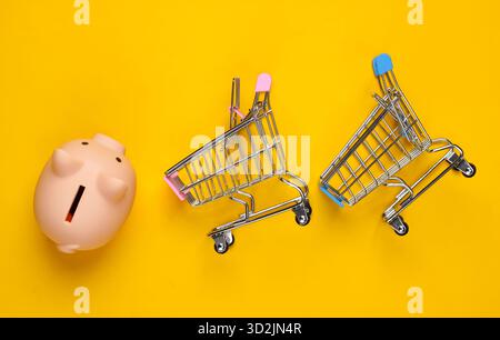 Schweinebank und zwei Mini-Supermarkt-Trolley auf gelbem Hintergrund. Minimalistische Studioaufnahme. Draufsicht. Flache Lagen. Stockfoto