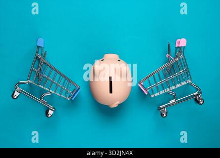 Schweinebank und zwei Mini-Supermarkt-Trolley auf blauem Hintergrund. Minimalistische Studioaufnahme. Draufsicht. Flache Lagen. Stockfoto