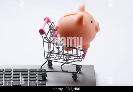 Einkaufswagen mit Piggy Bank auf Laptop-Tastatur Nahaufnahme Stockfoto