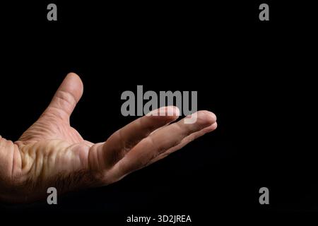 Mann mittleren Alters mit faltiger Haut, die ein unsichtbares, schwimmendes Kosmetikprodukt auf Schwarz isoliert hält Stockfoto