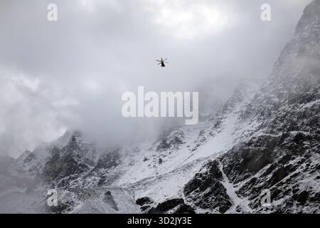 Bozen, Italien. November 2025. Ein Bergrettungshubschrauber fliegt vor dem verschneiten Ortlergebirge auf der Suche nach zwei vermissten Bergsteigern. Nach dem Tod von mindestens drei deutschen Bergsteigern bei einem Lawinenunfall in Südtirol wurde die Suche nach zwei Vermissten wieder aufgenommen. Quelle: Karl-Josef Hildenbrand/dpa/Alamy Live News Stockfoto