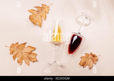 Weingläser mit Herbstlaub auf beigem Hintergrund, Herbstkomposition Stockfoto
