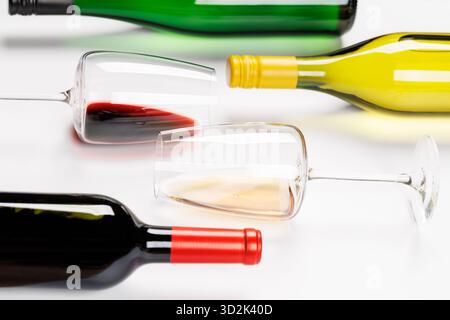 Weingläser mit Rot- und Weißwein und Flaschen auf weißem Hintergrund, minimalistischer eleganter Stil Stockfoto