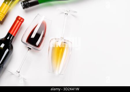 Weingläser mit Rot- und Weißwein und Flaschen auf weißem Hintergrund, minimalistischer eleganter Stil Stockfoto