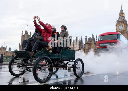 Westminster, London, Großbritannien. November 2025. Die Rennstrecke von London nach Brighton ist das am längsten laufende Motorrennen der Welt. Das erste Rennen fand nach der Gesetzesänderung statt, die es „leichten Lokomotiven“ ermöglichte, mit Geschwindigkeiten von mehr als 4 km/h zu fahren. Die Verabschiedung des Gesetzes im Parlament wurde mit der ersten Fahrt am 14. November 1896 gefeiert, bei der 30 Autos nach Brighton fuhren. Es sind rund 400 Fahrzeuge beteiligt, die vor 1905 gebaut worden sein müssen. Die Fahrzeuge fuhren bei nassem Sonnenaufgang vom Hyde Park aus durch London. 1903 Stanley (Steam) Auto, vorbei am Parlament, machte ein Selfie Stockfoto