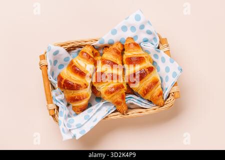 Frisch gebackene Croissants in Korb auf hellem Hintergrund, gemütliches Frühstück Stockfoto