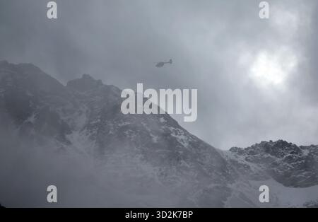 Bozen, Italien. November 2025. Ein Bergrettungshubschrauber fliegt vor dem verschneiten Ortlergebirge auf der Suche nach zwei vermissten Bergsteigern. Nach dem Lawinenunfall in Südtirol wurden auch die Leichen der beiden noch vermissten Deutschen gefunden. Es ist nun sicher, dass am Vortag insgesamt fünf Bergsteiger bei dem Unfall ums Leben kamen - alle aus Deutschland. Quelle: Karl-Josef Hildenbrand/dpa/Alamy Live News Stockfoto