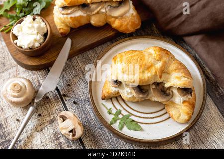 Frisch gebackene Croissants mit Pilzen und Ricotta auf rustikalem Holztisch. Stockfoto