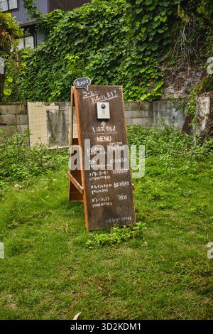Menü eines Coffeeshops auf einem gefalteten Holzständer mit Videosprechanlage für Kundenbestellungen in Onomichi, Japan Stockfoto