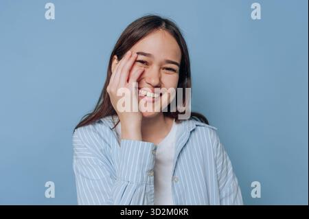 Lächelnde Frau in blau gestreiftem Hemd auf blauem Hintergrund. Stockfoto