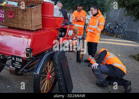 RAC-Mitarbeiter untersuchen den 1904er Stanley Stream-Oldtimer von Andy Green, der Weltrekordhalter des Landgeschwindigkeitsrekordes ist, in Brixton auf ihrer Route für die jährliche Rallye London nach Brighton am 2. November 2025 in London, England. Der ehemalige RAF-Jagdpilot, Wing Commander Andy Green, wurde 1997 zum schnellsten Mann der Welt und bleibt der aktuelle Besitzer des World Land Speed Record und der erste Mensch, der jemals mit Überschallgeschwindigkeiten von 763,035 mph (mach .016) im Thrust SSC gefahren wurde. Green wurde von seiner Frau Emma in ihrem Stanley Stream, welches entwickelt wurde, begleitet Stockfoto