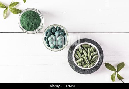 Drei Gläser mit Spirulina-Produkt aus organischen grünen Algen in Tabletten, Kapseln, Pulver. Eine Alternative zur Medizin. Draufsicht. Weißer Hintergrund Stockfoto