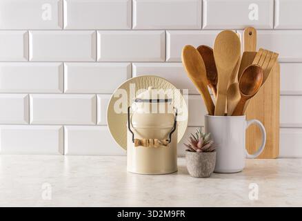 Stilvoller Küchenhintergrund in hellen Farben mit stilvollen Küchenutensilien in minimalistischem Stil. Vorderansicht. Eine Kopie des Bereichs. Weiße Ziegelwand Stockfoto