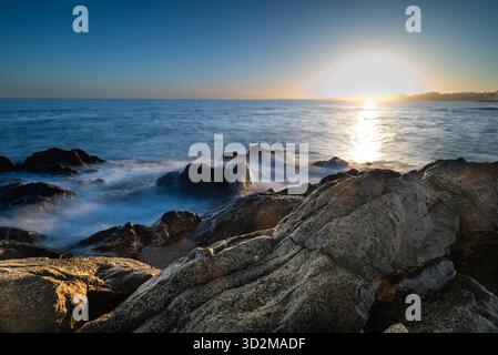 Dramatischer Sonnenuntergang über dem Atlantischen Ozean mit Wellen, die gegen vulkanische Felsen auf Gran Canaria, den Kanarischen Inseln, Spanien brechen. Stockfoto