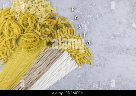 Draufsicht auf verschiedene Arten von trockenen Nudeln und Nudeln auf grauem Hintergrund. Buchstaben – Einfügen Stockfoto